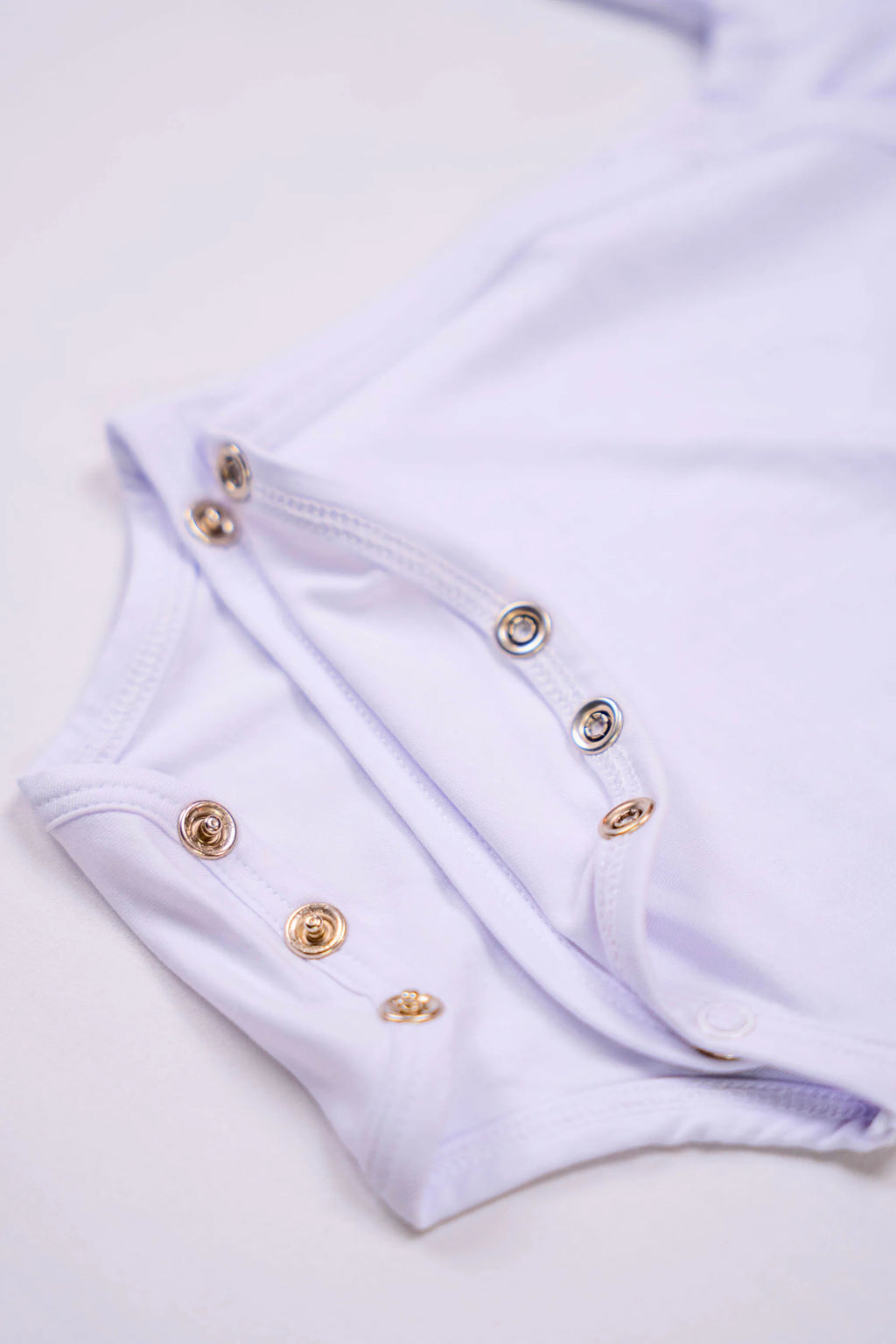 Bodies Blanc Neige avec zoom sur les boutons pressions de fermeture.