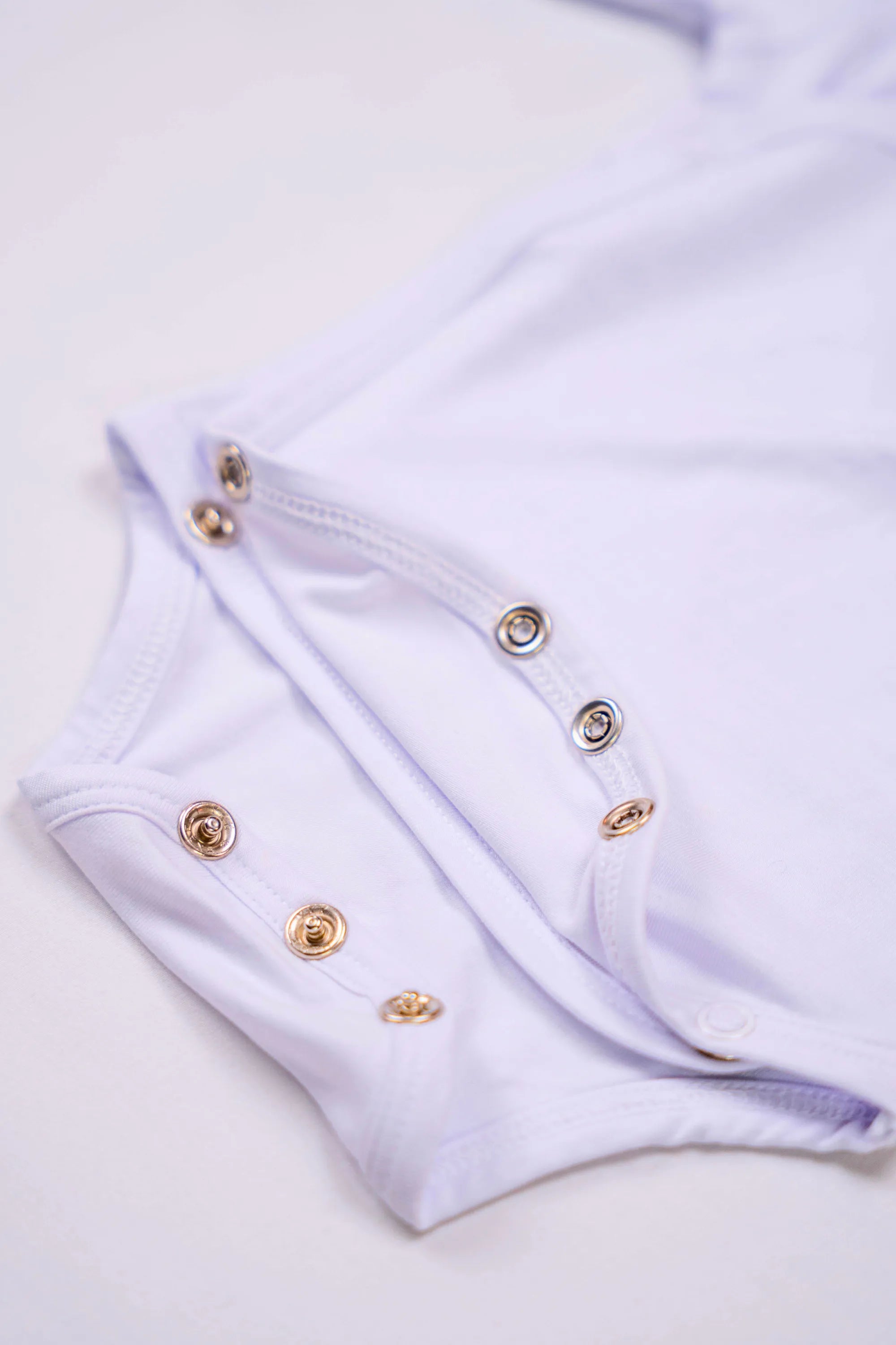 Bodies Blanc Neige avec zoom sur les boutons pressions de fermeture.